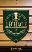 Load image into Gallery viewer, Decorative sign for &#39;The 19th Hole&#39; with golf-themed design on a wooden background.
