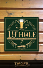 Load image into Gallery viewer, Decorative sign for &#39;The 19th Hole&#39; with a green background and gold text, featuring a beer glass and golf club design, on a wooden wall.
