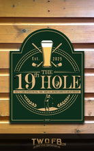 Load image into Gallery viewer, Decorative sign for &#39;The 19th Hole&#39; with a beer glass and golf elements on a wooden background.
