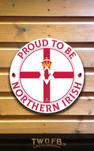 Load image into Gallery viewer, Circular sign with &#39;Proud to be Northern Irish&#39; text on a wooden background
