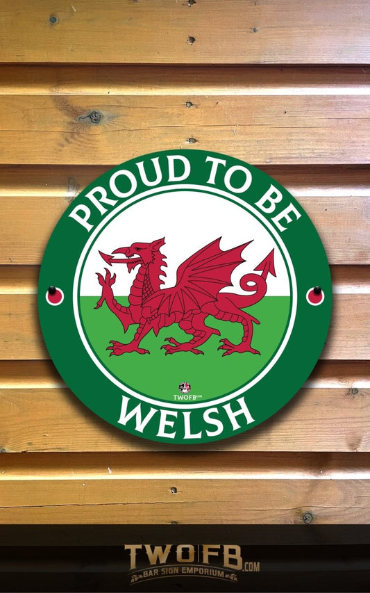 Round sign with red dragon and 'Proud to be Welsh' text on a wooden background