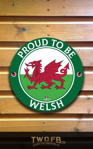Round sign with red dragon and 'Proud to be Welsh' text on a wooden background